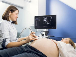 Young pregnant woman having ultrasound to monitor fetal development