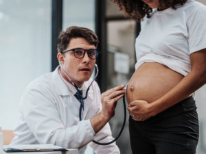 gynecologist checking a pregnant woman to help manage a high-risk pregnancy