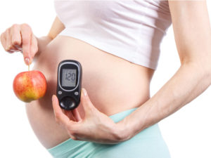 pregnant woman holding a glucose meter to keep track of possible gestational diabetes in a high-risk pregnancy