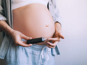 Pregnant woman doing a finger prick test to illustrate managing a gestational diabetes diet