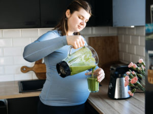 pregnant woman preparing green smoothie as part of gestational diabetes diet plan