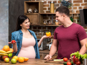 young couple smiling happily with a healthy range of foods for gestational diabetes