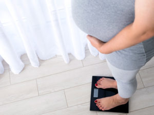 pregnant woman on scales to illustrate controlling weight with diet during gestational diabetes