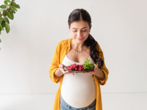 pregnant woman holding plate of food showing increased appetite and energy during second trimester