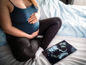 Pregnant woman on bed reviewing ultrasound scan to illustrate second trimester of pregnancy