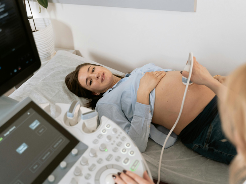 pregnant woman lying down having an ultrasound check to illustrate how many ultrasounds you get while pregnant