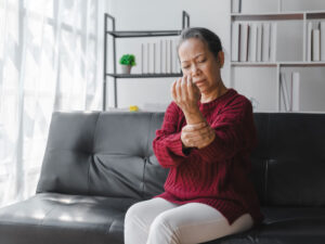 elderly lady on sofa examining wrist for osteoporosis