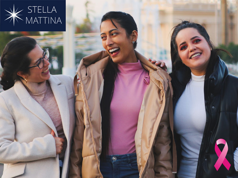 Three smiling women and a breast cancer pink ribbon to illustrate learning about first mammogram appointments