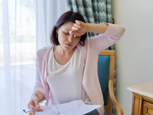 stressed woman with headache to illustrate symptoms of menopause