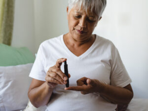 mixed race female checking blood sugar levels with a finger stab