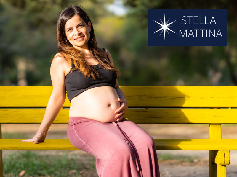 Young pregnant woman on a park bench with hand on stomach to illustrate enjoying a healthy pregnancy