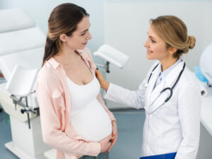 Smiling pregnant woman consulting gynecologist in clinic to illustrate prevention and care of sexually transmitted diseases during pregnancy