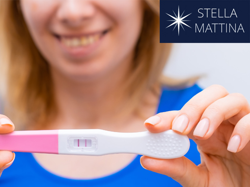 smiling woman holding a positive test result to illustrate where to find a pregnancy test near me