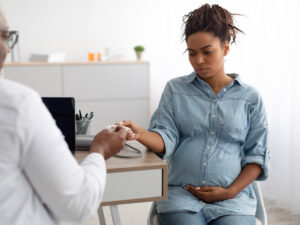 doctor giving out tablets to a pregnant patient to illustrating the importance of treating HIV in pregnancy