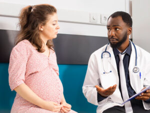 doctor talking to a pregnant female to illustrate first OBGYN visit
