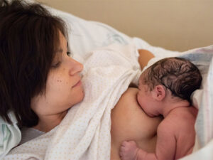 Young mom feeding her newborn to illustrate breastfeeding benefits immediately after birth