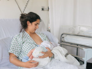 Mother breastfeeding newborn in hospital bed