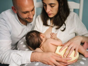 father supporting mom to breastfeed their newborn to illustrate support for breastfeeding mothers