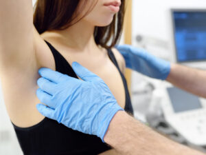 doctor examining a woman's breasts to illustrate taking notice of warning signs of breast cancer