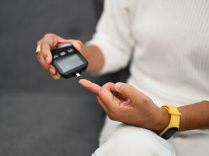 woman taking a finger prick blood test to illustrate how insulin affects weight gain and loss