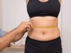 nutritionist measuring a woman's waist too assess her ideal weight