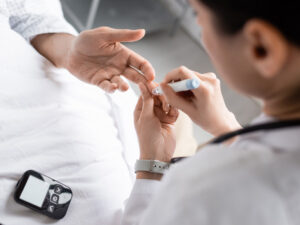 doctor testing a patient for diabetes with a finger prick to assess a health risk in pregnancy