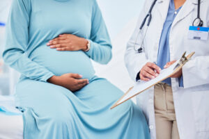 doctor with clipboard in discussion with pregnant patient to illustrate high-risk pregnancy care